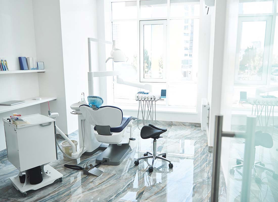 Dental Practice Insurance - Empty Bright and Light Stomatological Room and Dentist Chair in a Modern Office Awaiting the Next Patient